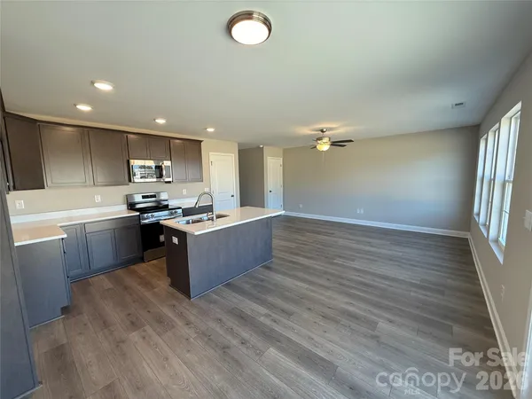 a kitchen with stainless steel appliances granite countertop a sink counter space cabinets and a wooden floor