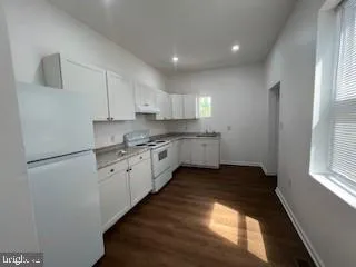 a kitchen with granite countertop white cabinets and white appliances
