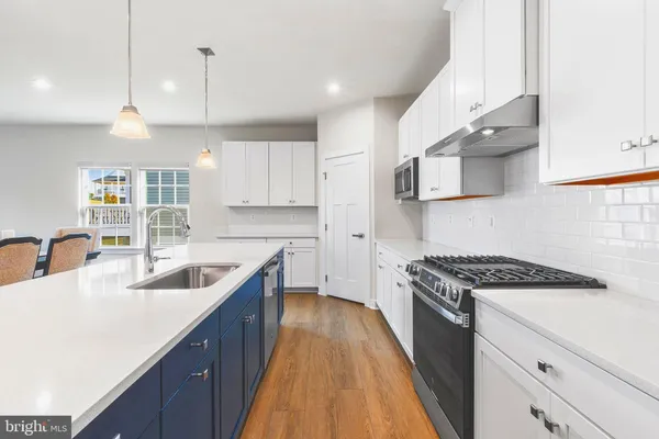 a kitchen with kitchen island a sink stainless steel appliances and white cabinets