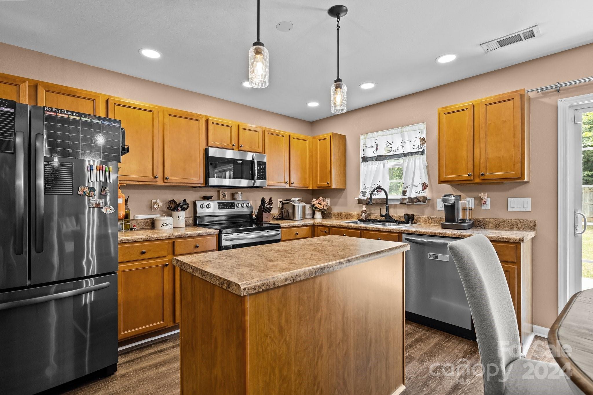 5511 Keener Ridge Road Charlotte, NC 28216 - Photo 23 of 31 a kitchen with stainless steel appliances granite countertop a refrigerator a sink dishwasher a stove top oven a kitchen island and couches with wooden floor