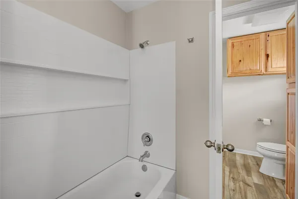 a hallway with granite countertop white cabinets and a wooden floor