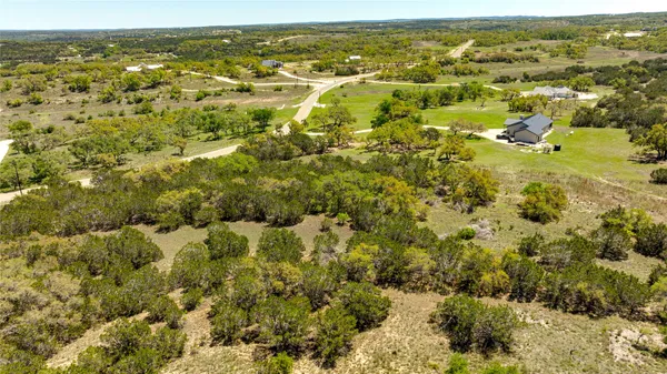 an aerial view of residential houses with outdoor space and trees