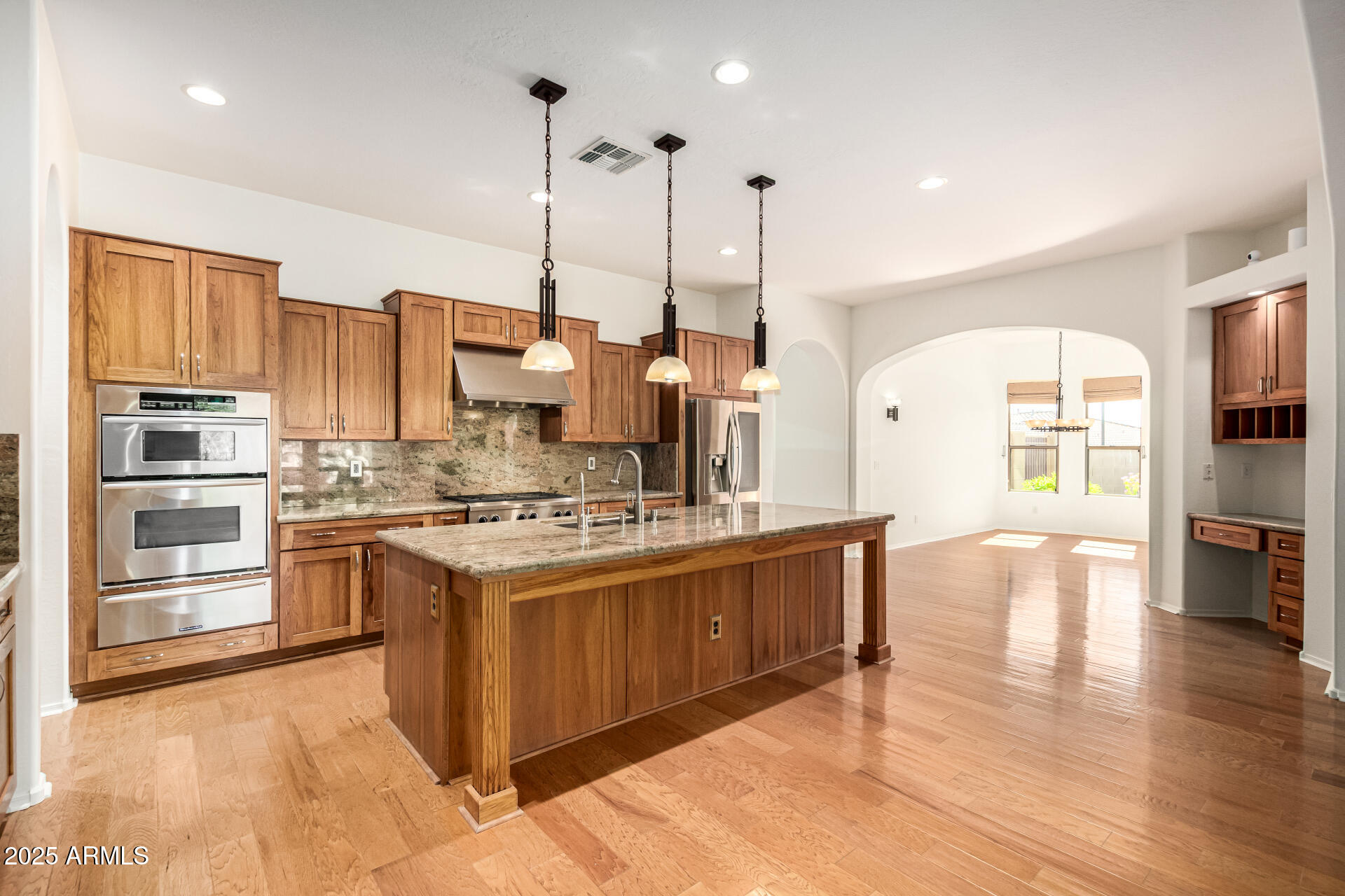 16030 South 27th Drive Phoenix, AZ 85045 - Photo 9 of 29 a kitchen with stainless steel appliances granite countertop a stove top oven a sink dishwasher a dining table and chairs with wooden floor