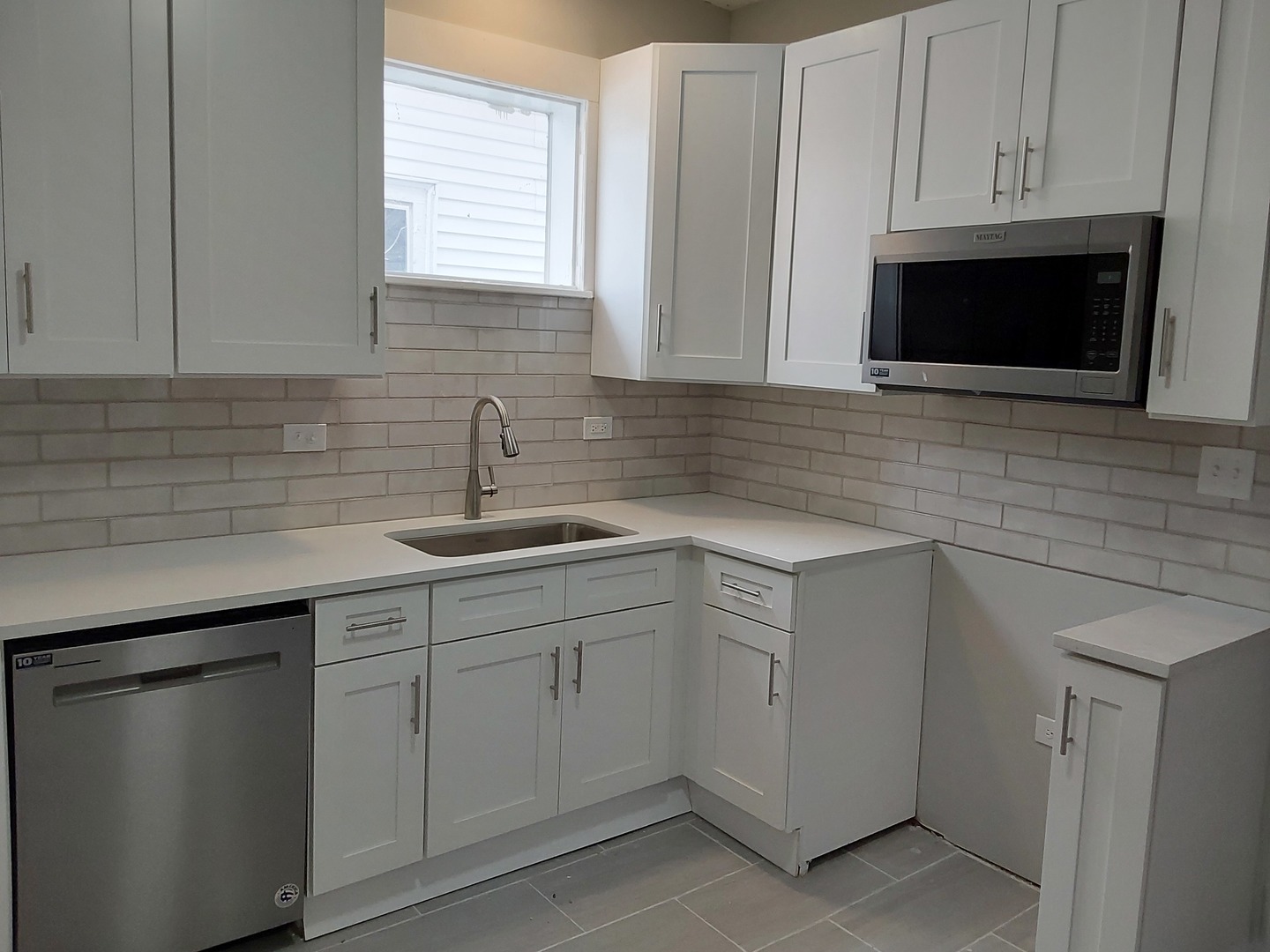 7712 South Evans Avenue Chicago, IL 60619 - Photo 8 of 22 a kitchen with white cabinets appliances a sink and a window