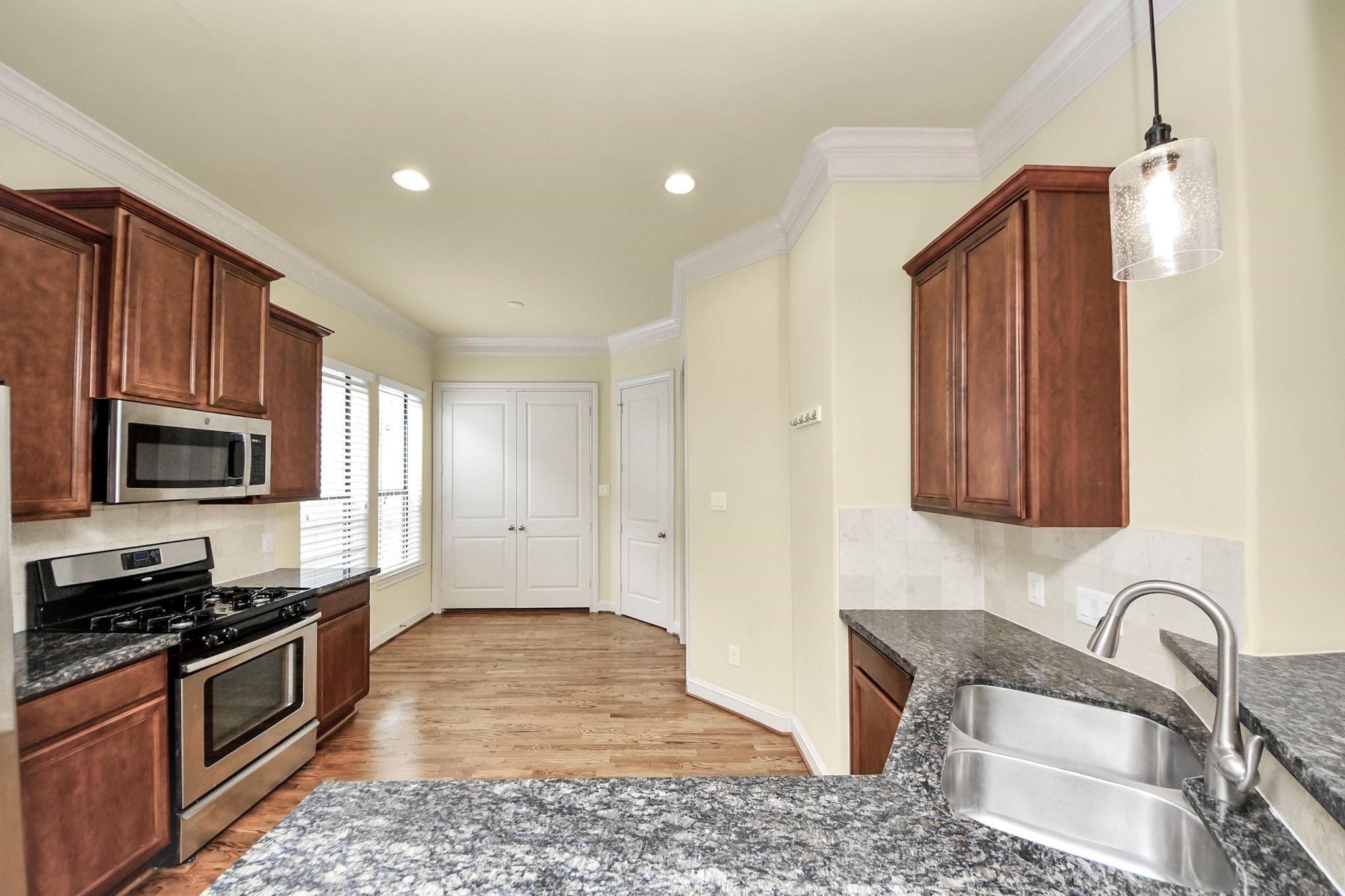 5617 Kiam Street, Unit A Houston, TX 77007 - Photo 16 of 46 a kitchen with granite countertop wooden cabinets a stove top oven and stainless steel appliances