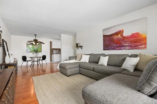 a living room with furniture and a dining table with wooden floor