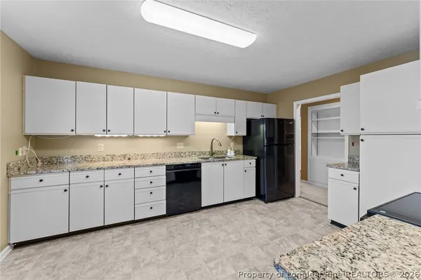 a kitchen with granite countertop a refrigerator and a stove top oven