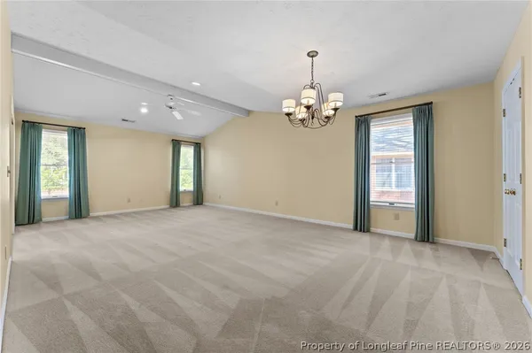 a view of an empty room with window and chandelier