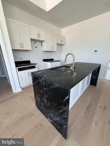 a kitchen with kitchen island granite countertop a stove top oven a sink and white cabinets