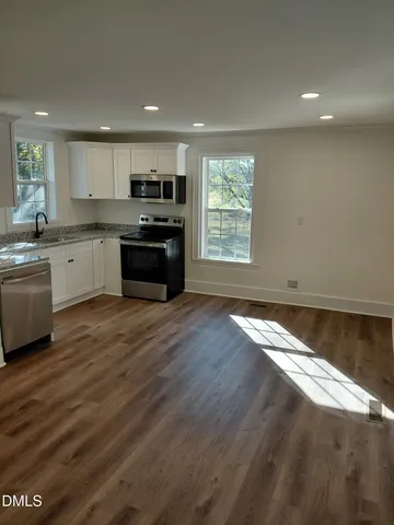 a large kitchen with kitchen island granite countertop a stove top oven a sink with wooden floors