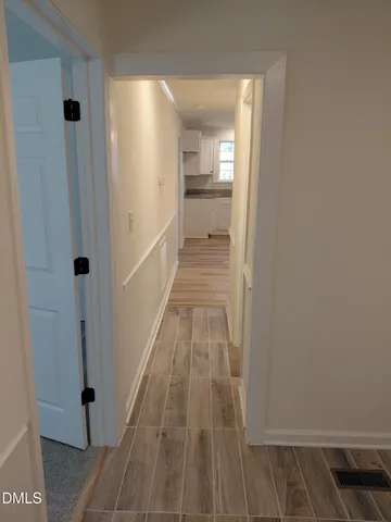 a view of a hallway with wooden floor and a bathroom