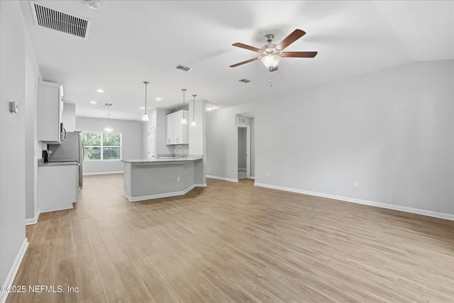 a view of a big room with wooden floor and a kitchen