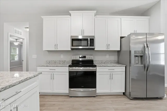 a kitchen with stainless steel appliances granite countertop a stove a refrigerator and a microwave