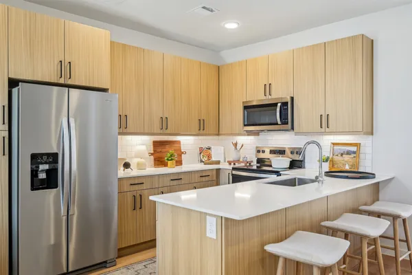 a kitchen with stainless steel appliances a refrigerator a sink a stove a microwave a counter space and cabinets