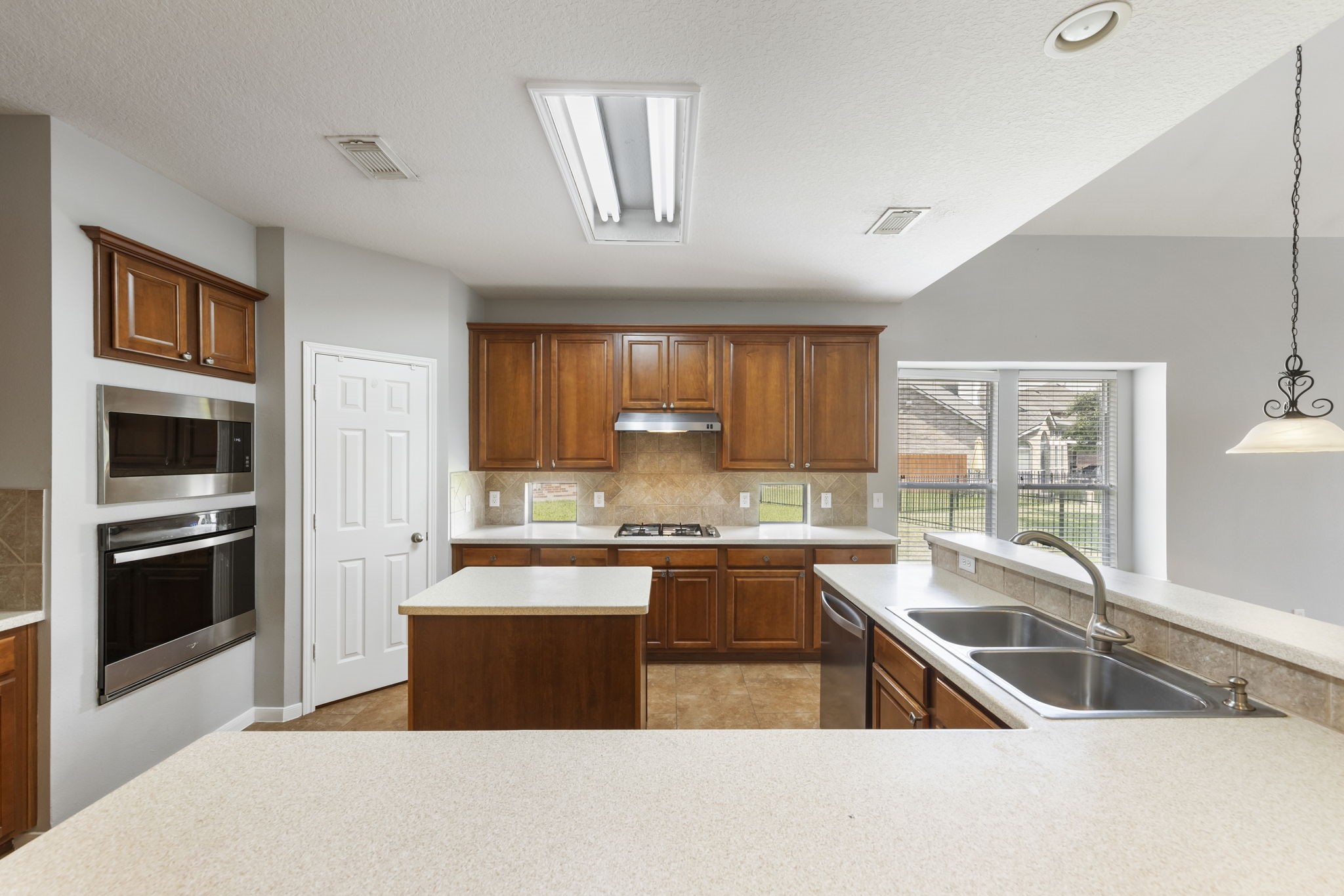 2907 Stemwood Drive Spring, TX 77388 - Photo 7 of 33 Open-concept kitchen designed for both functionality and entertaining, featuring rich wood cabinetry, expansive prep space, center island, stainless steel appliances, and breakfast bar seating overlooking the living area and waterfront backyard.