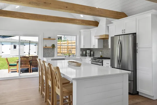 a kitchen with stainless steel appliances a dining table chairs and a refrigerator