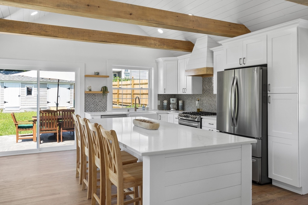 a kitchen with stainless steel appliances a dining table chairs and a refrigerator