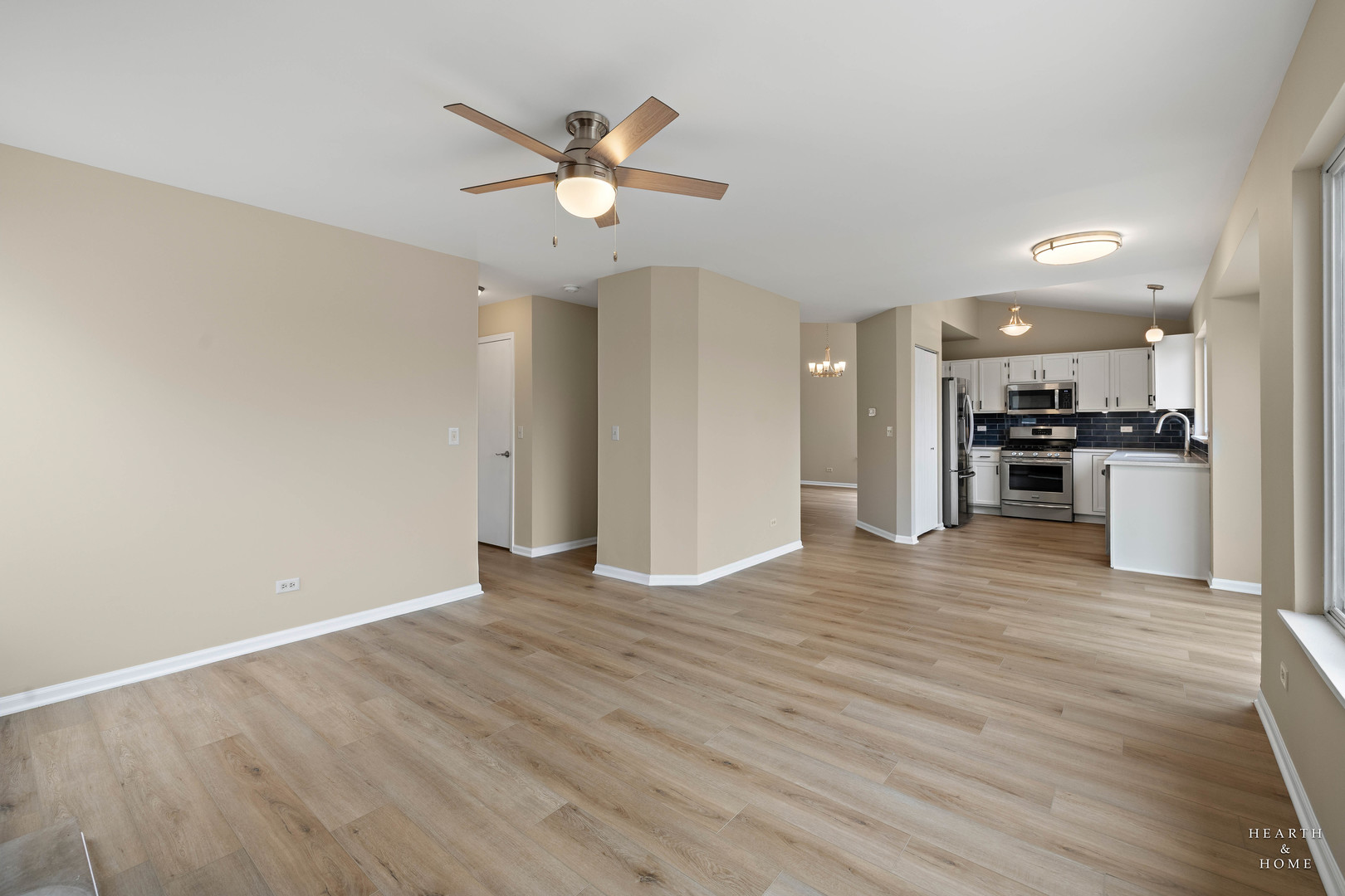 305 Harvest Gate Road Lake In The Hills, IL 60156 - Photo 13 of 36 an empty room with wooden floor a ceiling fan and kitchen view