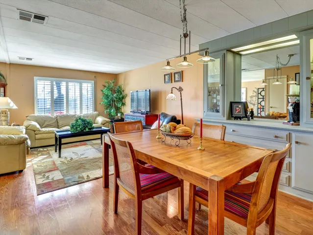 a view of a dining room and livingroom with furniture wooden floor a rug a potted plant and a chandelier