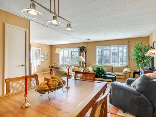 a living room with furniture kitchen view and large windows