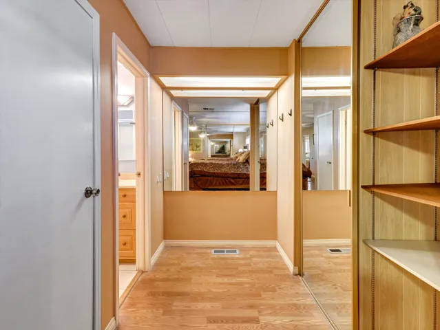 a view of a hallway with wooden floor and a bathroom