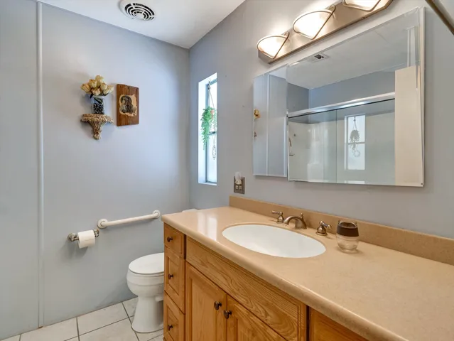 a bathroom with a granite countertop sink a toilet and a mirror