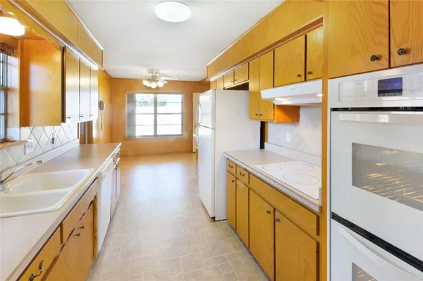 a kitchen with granite countertop a sink a stove and a wooden cabinets
