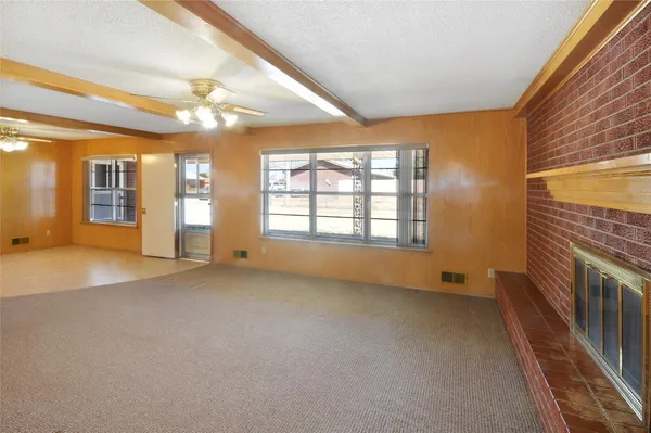 a view of an empty room with a fireplace and a window