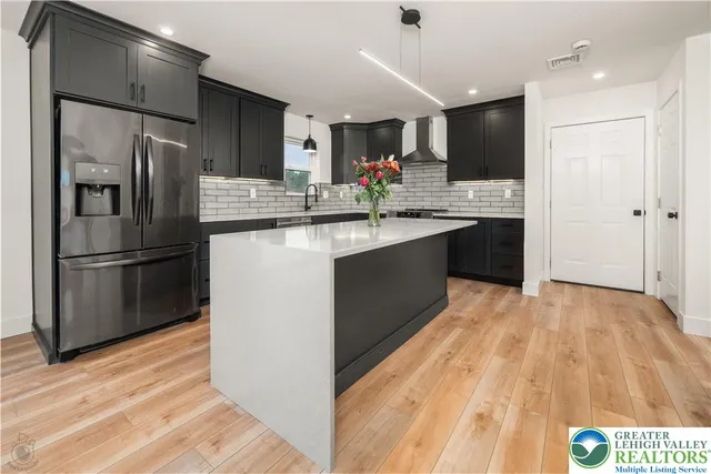 a kitchen with stainless steel appliances granite countertop a sink cabinets and wooden floor