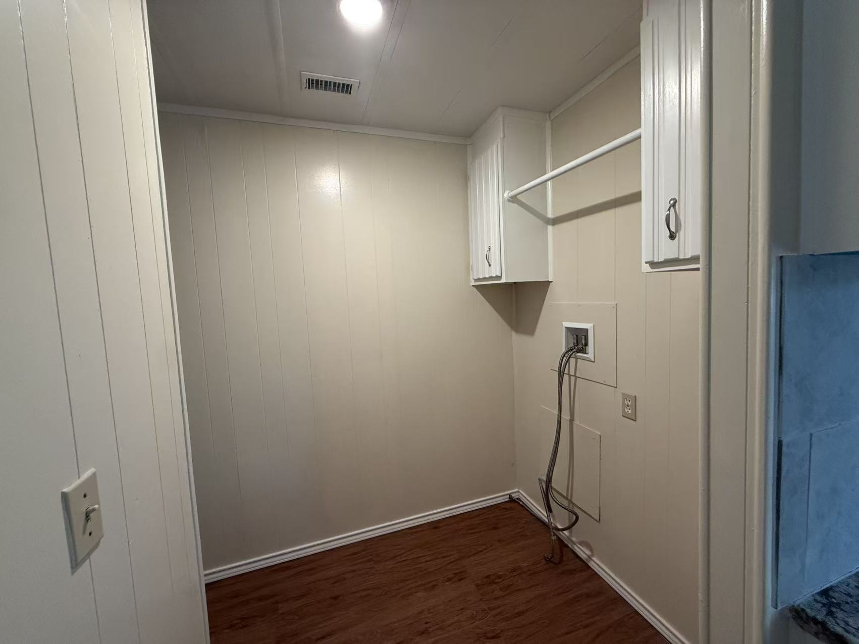 23393 Nameless Road, Unit 113 Leander, TX 78641 - Photo 11 of 16 Laundry area with dark wood-style floors, wooden walls, washer hookup, and cabinet space