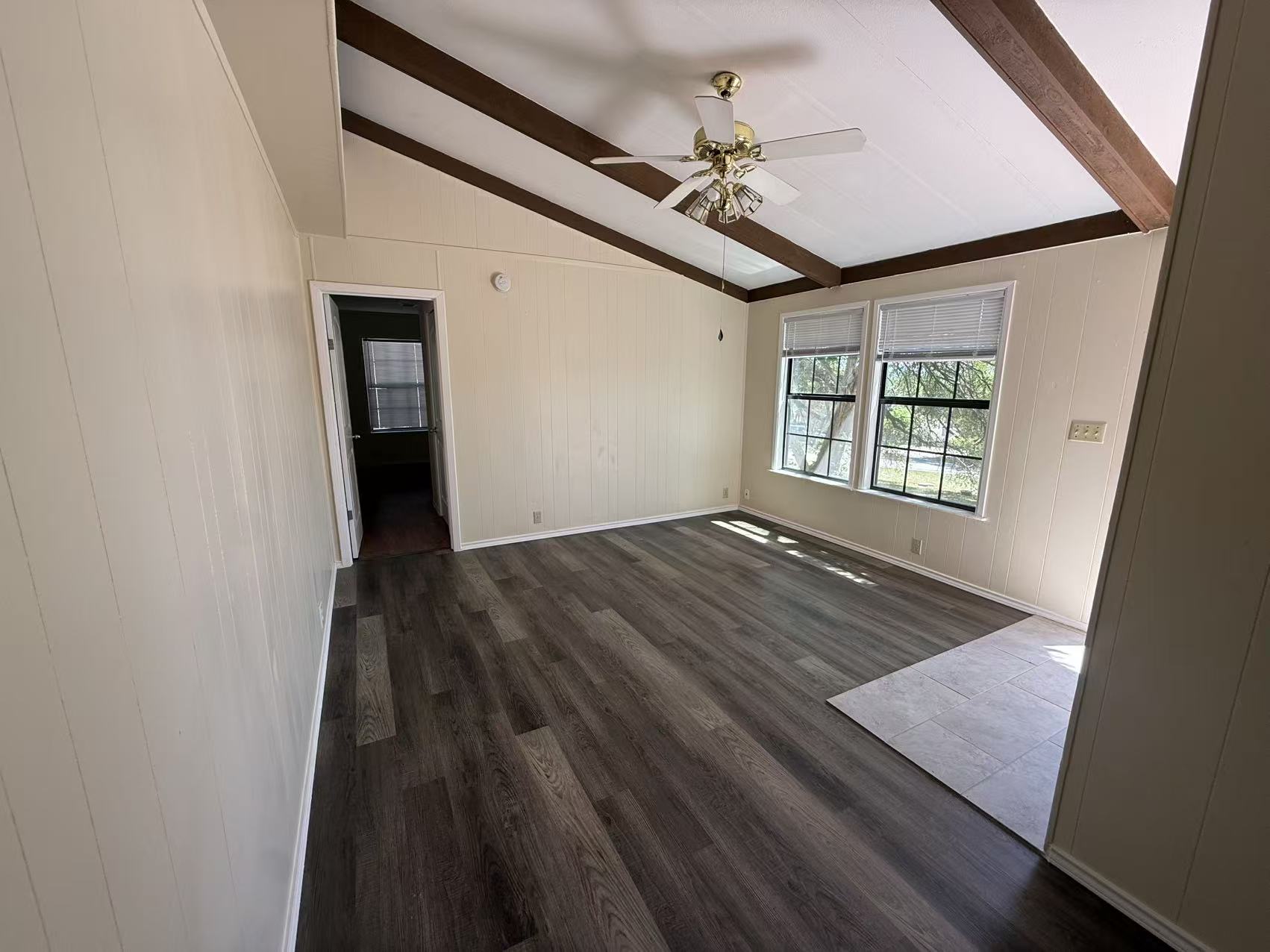 23393 Nameless Road, Unit 113 Leander, TX 78641 - Photo 3 of 16 Empty room featuring a ceiling fan, dark wood-type flooring, lofted ceiling with beams, and wood walls
