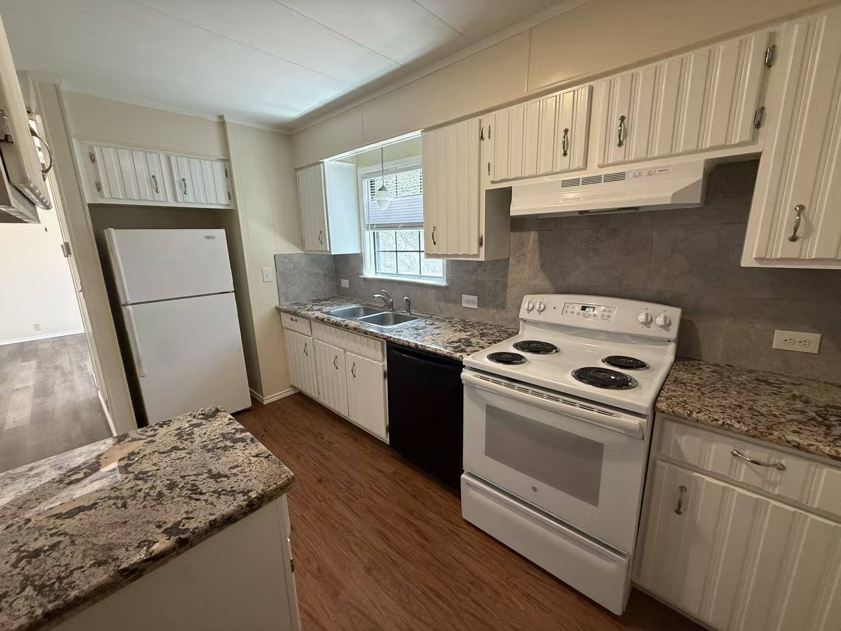 23393 Nameless Road, Unit 113 Leander, TX 78641 - Photo 9 of 16 Kitchen with white appliances, backsplash, dark wood finished floors, light stone counters, and ornamental molding