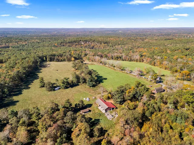 an aerial view of a house with garden space and trees all around