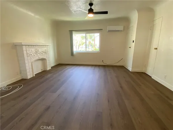 an empty room with wooden floor fireplace and windows