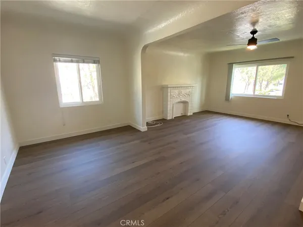 an empty room with wooden floor cabinet and windows