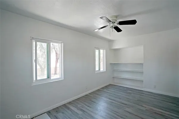 a view of an empty room with a window and wooden floor