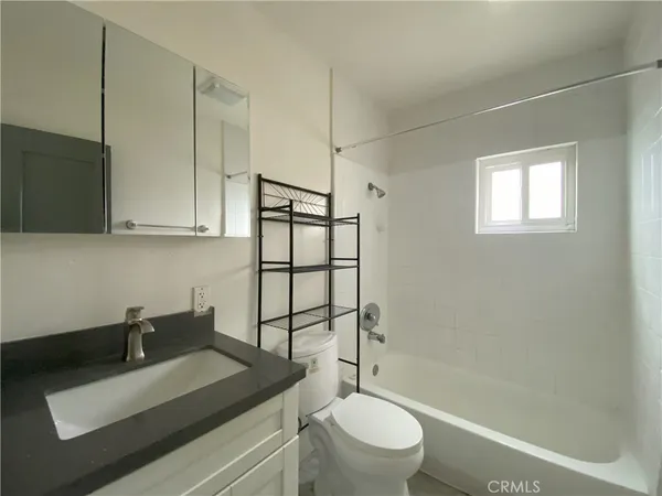 a bathroom with a granite countertop sink toilet mirror and shower