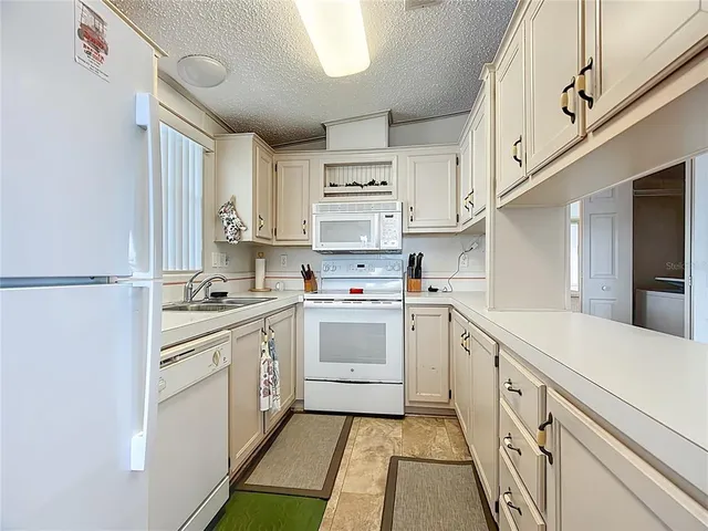 a kitchen with granite countertop white cabinets and white appliances