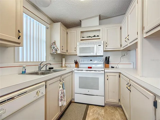 a kitchen with granite countertop cabinets sink and white appliances