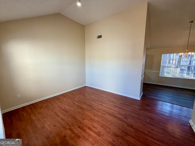 a view of an empty room with window and wooden floor