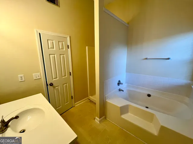 a bathroom with a tub sink and mirror