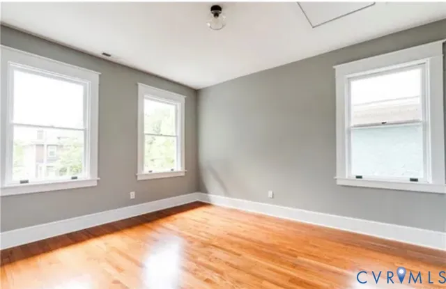 a view of an empty room with wooden floor and a window