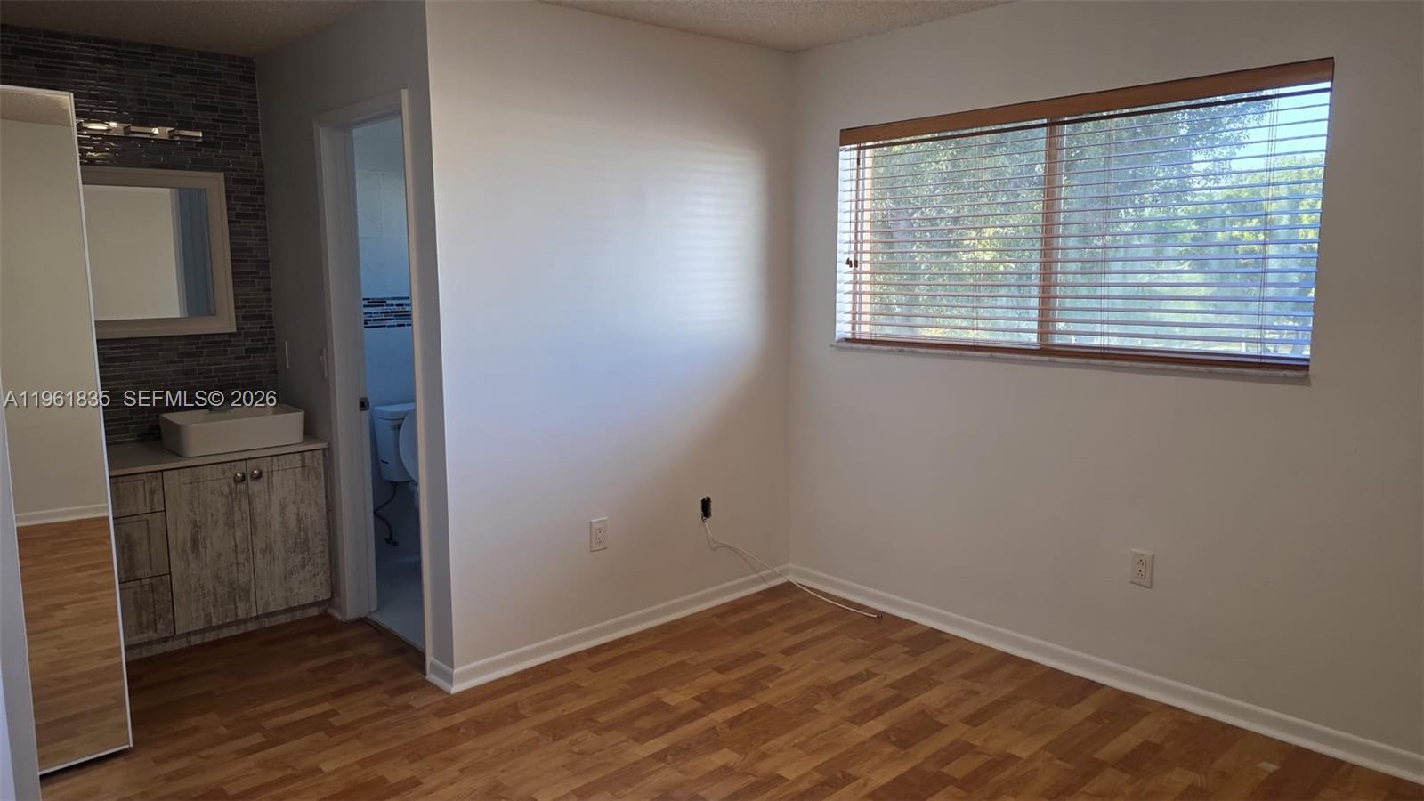 14905 Southwest 80th Street, Unit 217 Miami, FL 33193 - Photo 18 of 25 an empty room with wooden floor cabinet and windows
