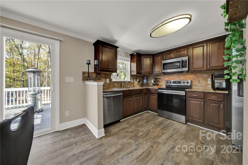 2430 Rice Planters Road Charlotte, NC 28273 - Photo 13 of 42 a kitchen with granite countertop a stove top oven a sink dishwasher a dining table and chairs with wooden floor