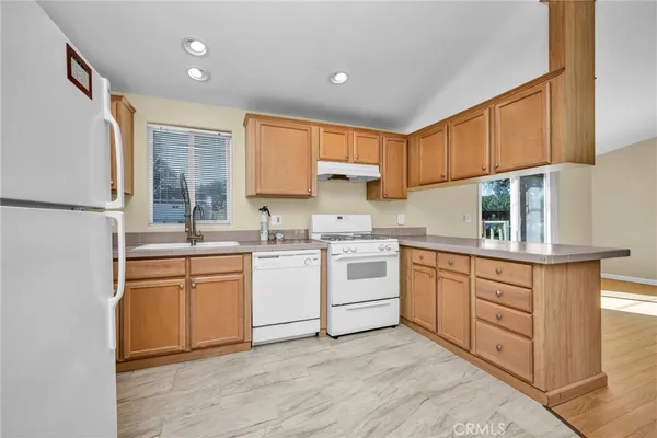 a kitchen with cabinets appliances a sink and a window