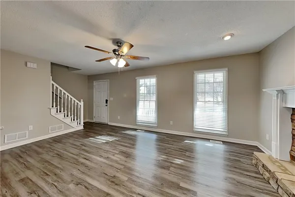 a view of an empty room with a window and wooden floor