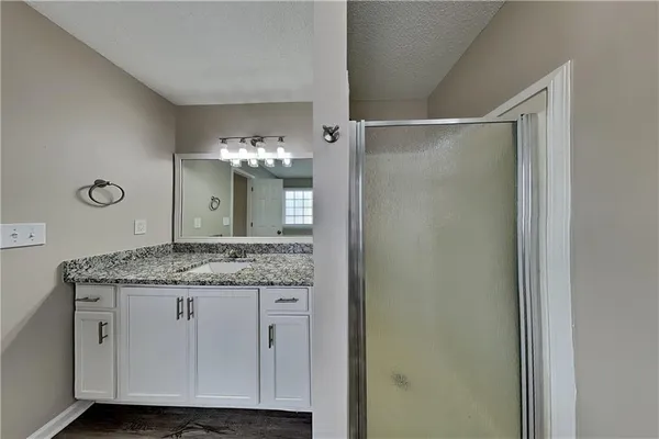 a bathroom with a granite countertop shower a sink and a mirror