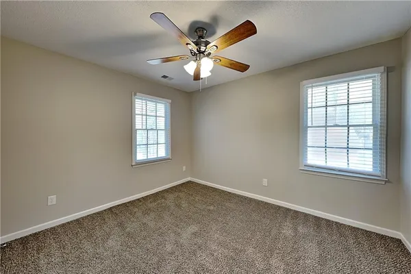 an empty room with windows and ceiling fan