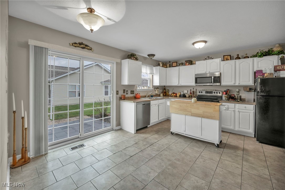 3887 Reeves Lane Medina, OH 44256 - Photo 17 of 42 Kitchen with sink, white cabinets, light tile patterned floors, and appliances with stainless steel finishes