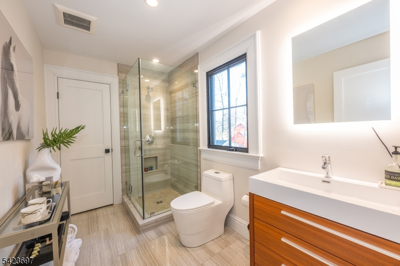45 Village Road New Vernon, NJ 07976 - Photo 31 of 49 a bathroom with a sink a toilet and a large mirror
